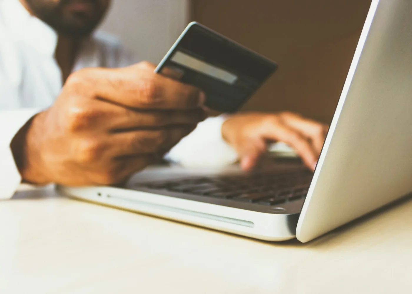 Person holding a bank card while working on a laptop